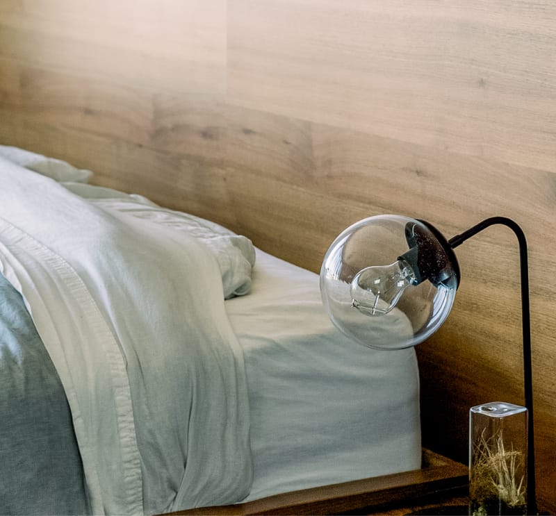 Detalle de dormitorio moderno con lámpara de diseño en madera, ejemplo de Home Staging en la Costa del Sol